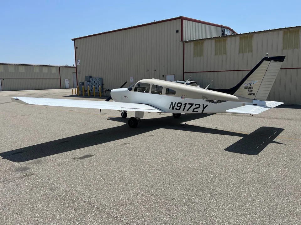 Rear-left view of Piper Warrior II N9172Y parked on the apron outside the hangar