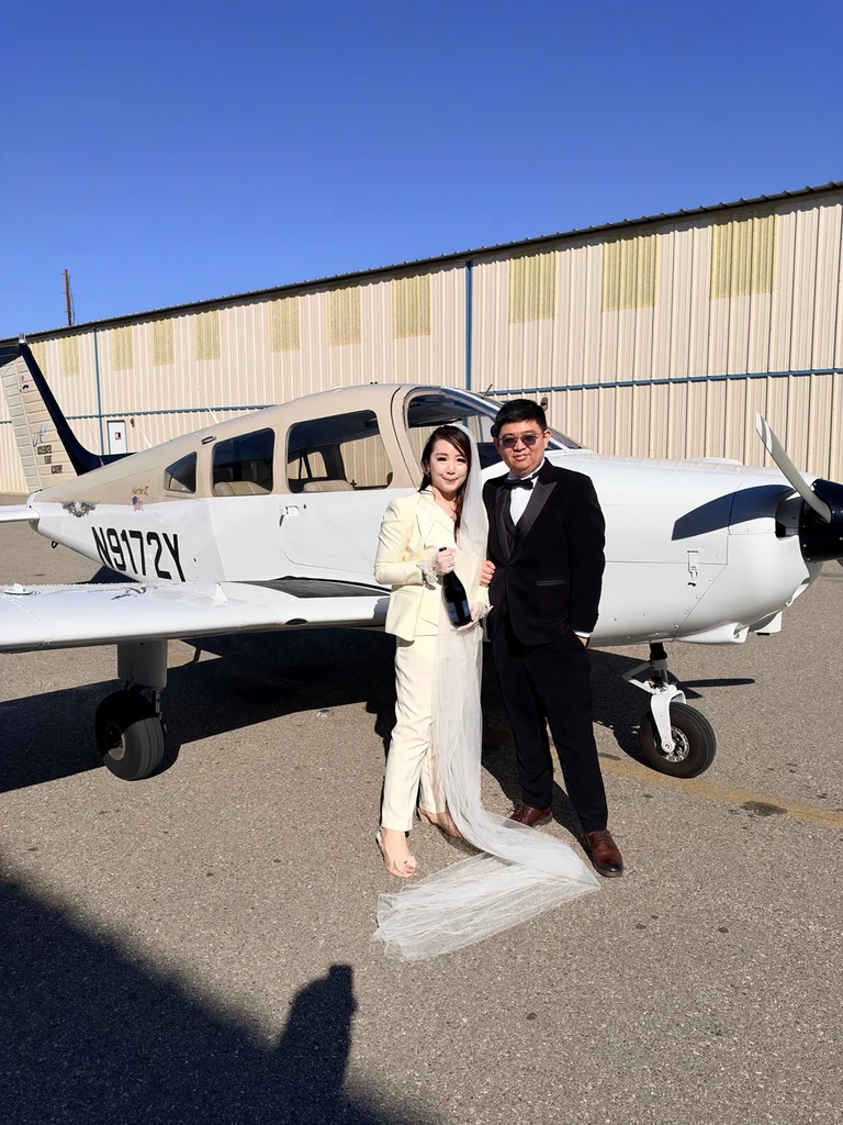 Couple in wedding attire posing beside Piper Warrior II N9172Y at Van Nuys Airport